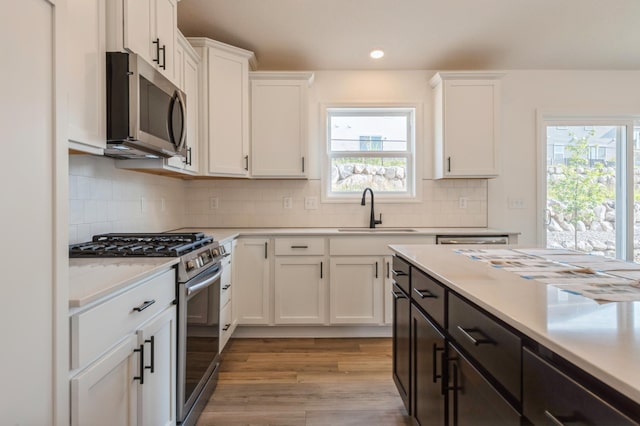 kitchen with white cabinets, appliances with stainless steel finishes, light wood-type flooring, and sink