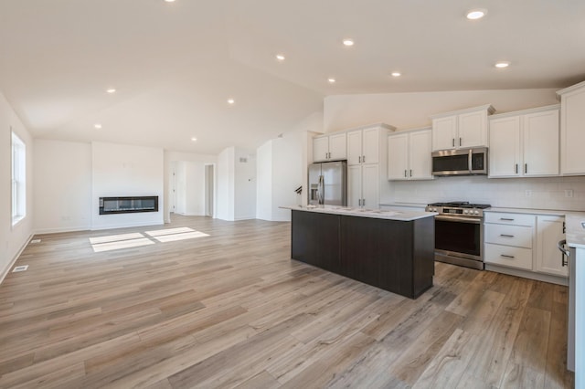 kitchen with white cabinetry, stainless steel appliances, tasteful backsplash, a kitchen island, and light wood-type flooring