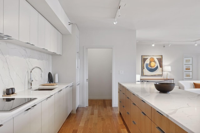 kitchen with white cabinetry, sink, light stone countertops, and black electric cooktop