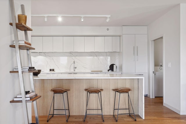 kitchen with a breakfast bar area, white cabinets, and decorative backsplash