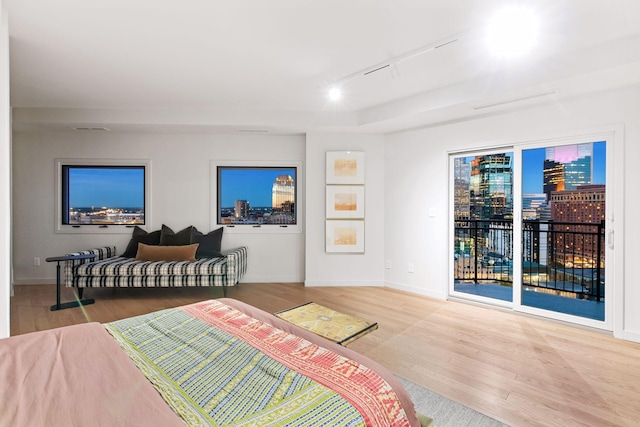 bedroom with access to outside, rail lighting, and wood-type flooring