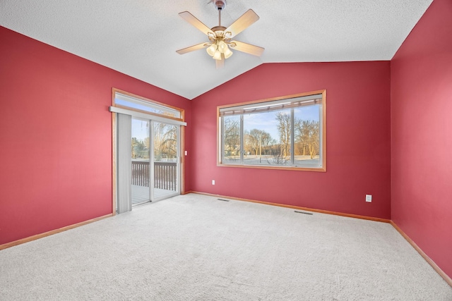 carpeted empty room featuring vaulted ceiling, a textured ceiling, and ceiling fan