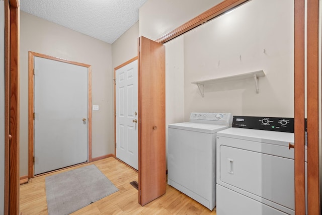 laundry room with light hardwood / wood-style floors, a textured ceiling, and independent washer and dryer