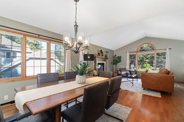 dining area featuring light hardwood / wood-style flooring, lofted ceiling, and a notable chandelier