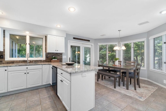 kitchen with backsplash, sink, decorative light fixtures, black dishwasher, and white cabinetry