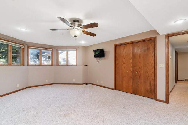 unfurnished bedroom featuring a closet, light colored carpet, multiple windows, and ceiling fan