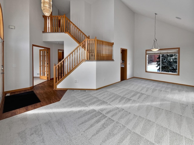 unfurnished living room featuring a high ceiling, a chandelier, and carpet flooring