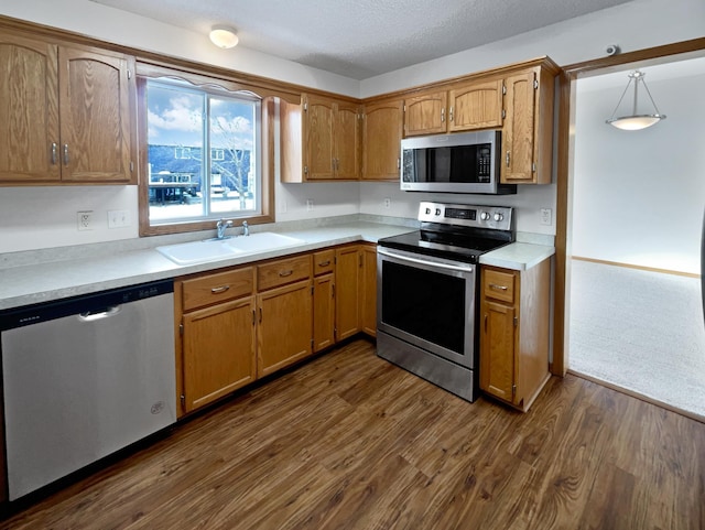 kitchen featuring stainless steel appliances, a textured ceiling, dark hardwood / wood-style floors, sink, and decorative light fixtures