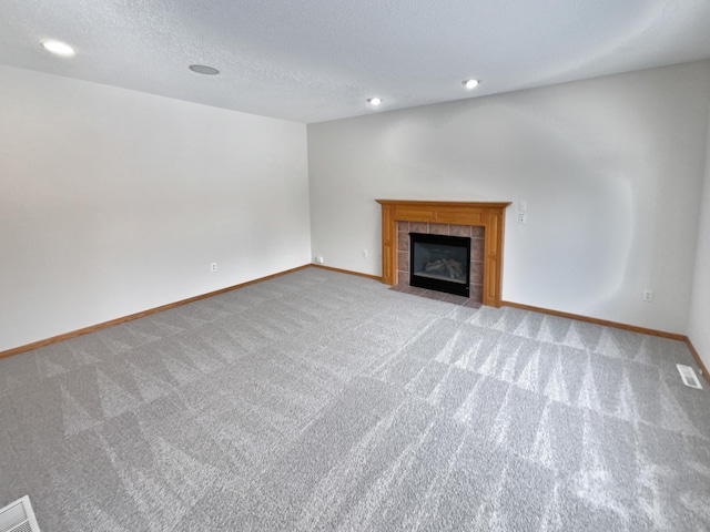 unfurnished living room with a fireplace, light colored carpet, and a textured ceiling