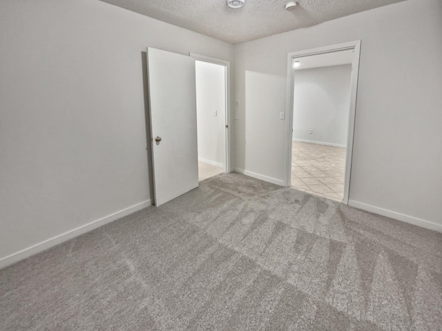 unfurnished bedroom featuring a textured ceiling and light carpet