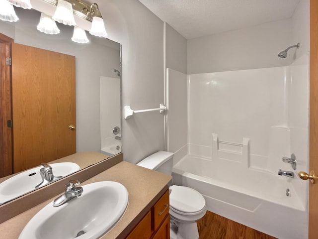 full bathroom featuring hardwood / wood-style floors, toilet, tub / shower combination, vanity, and a textured ceiling