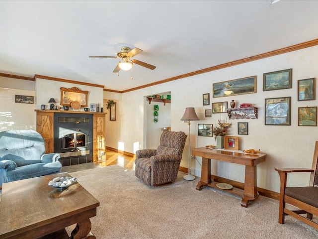 carpeted living room featuring a tiled fireplace, ornamental molding, and ceiling fan