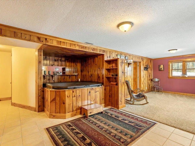 bar featuring light carpet, crown molding, wooden walls, and a textured ceiling