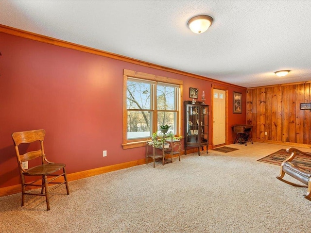 living area featuring light carpet, wooden walls, ornamental molding, and a textured ceiling