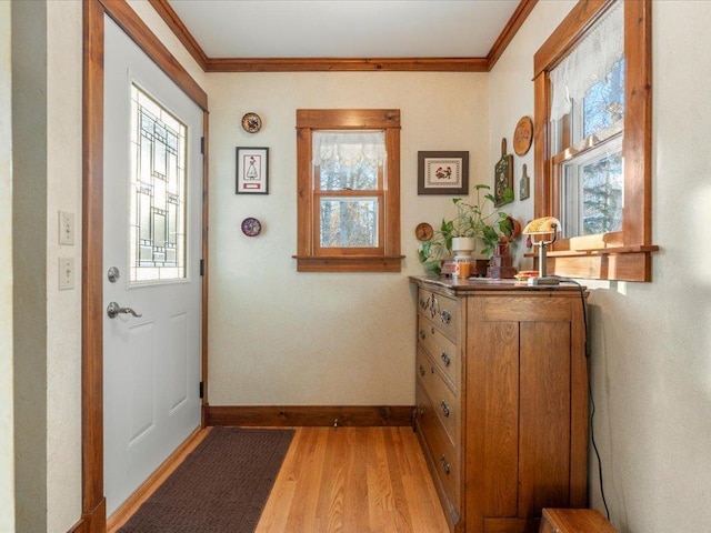 entryway featuring a healthy amount of sunlight, ornamental molding, and light wood-type flooring