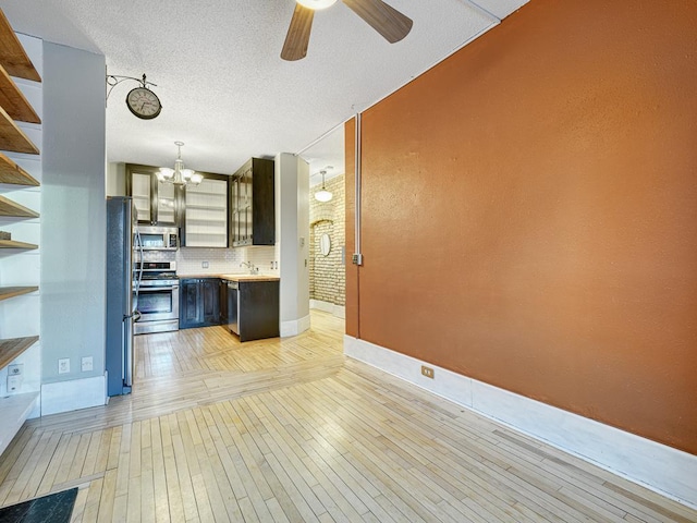 kitchen with light hardwood / wood-style floors, stainless steel appliances, decorative backsplash, sink, and ceiling fan with notable chandelier