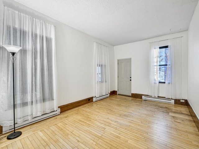 empty room featuring a textured ceiling, a baseboard radiator, and hardwood / wood-style floors