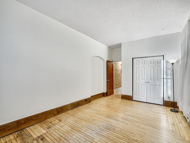 unfurnished bedroom featuring a textured ceiling, light hardwood / wood-style flooring, and a closet