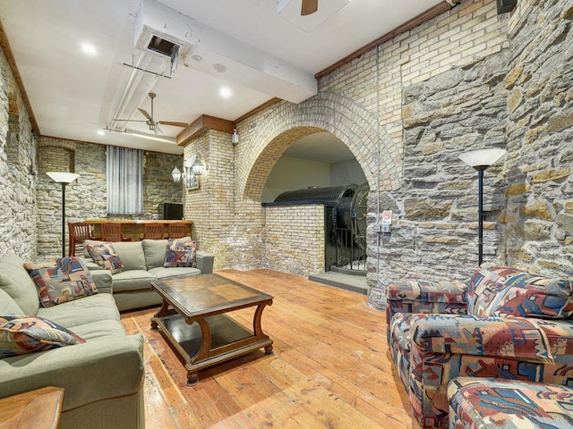 living room with ceiling fan, beamed ceiling, and wood-type flooring