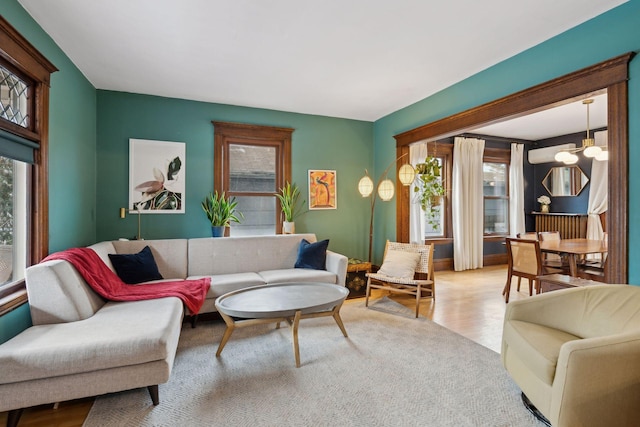 living room with plenty of natural light, an inviting chandelier, and light hardwood / wood-style flooring