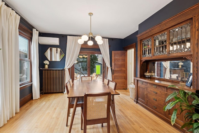 dining room featuring radiator, a wall unit AC, a chandelier, and a healthy amount of sunlight