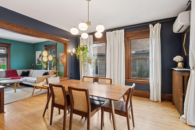 dining space featuring an inviting chandelier, a wall mounted air conditioner, and light hardwood / wood-style floors