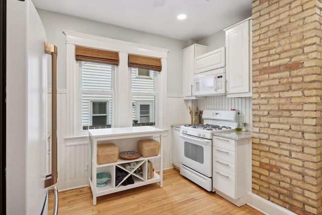 kitchen featuring brick wall, white cabinetry, light stone countertops, white appliances, and light hardwood / wood-style flooring