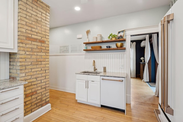 kitchen with sink, dishwasher, light hardwood / wood-style floors, light stone countertops, and white cabinets