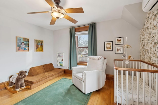 bedroom with lofted ceiling, hardwood / wood-style floors, a wall unit AC, and ceiling fan