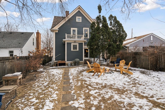 snow covered rear of property featuring a balcony