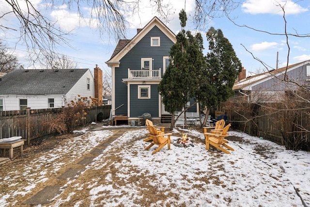 snow covered back of property featuring a balcony