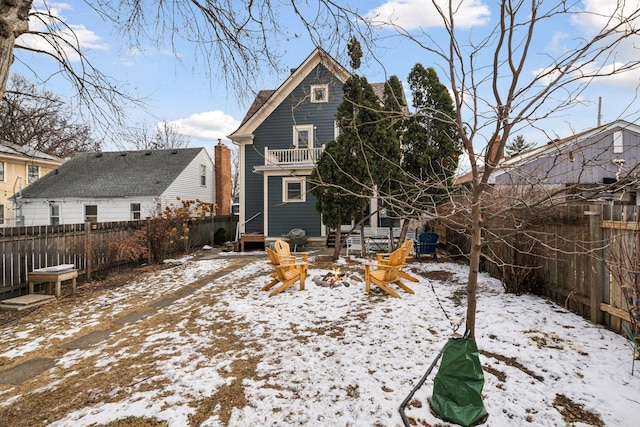 snow covered property featuring a balcony and a fire pit