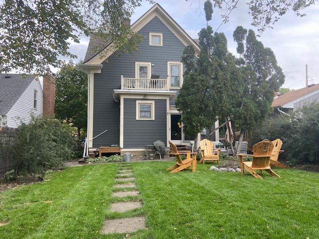 rear view of property featuring a balcony and a yard