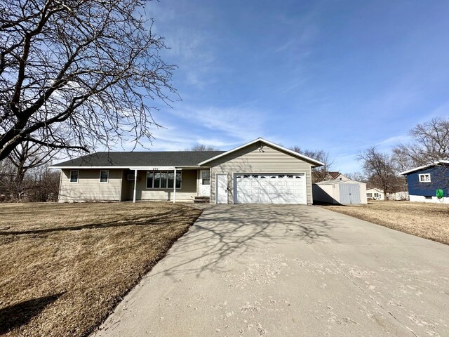 ranch-style house with a storage shed, concrete driveway, an attached garage, and a front lawn