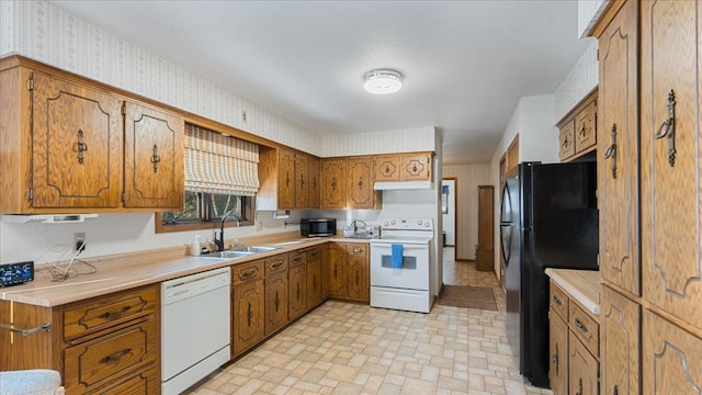 205 Ash St N, Sauk Centre, MN 56378 - kitchen featuring white appliances, a sink, brown cabinetry, wallpapered walls, and under cabinet range hood