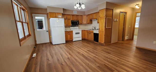 kitchen with sink, an inviting chandelier, white appliances, light hardwood / wood-style flooring, and hanging light fixtures