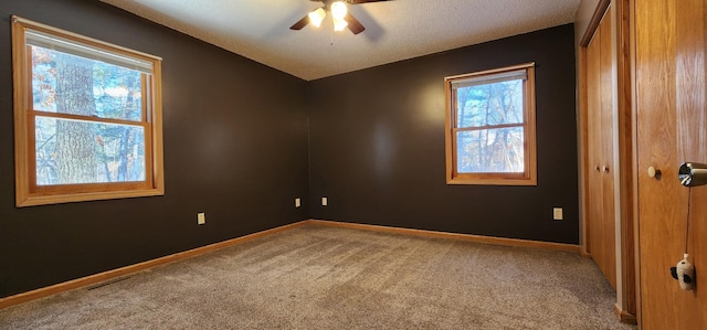 spare room with a textured ceiling, ceiling fan, and carpet