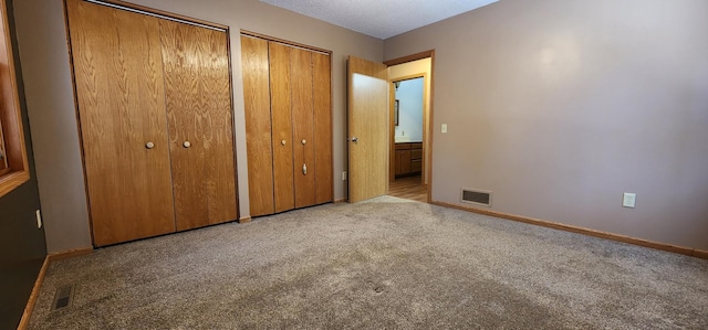 unfurnished bedroom with multiple closets and light carpet