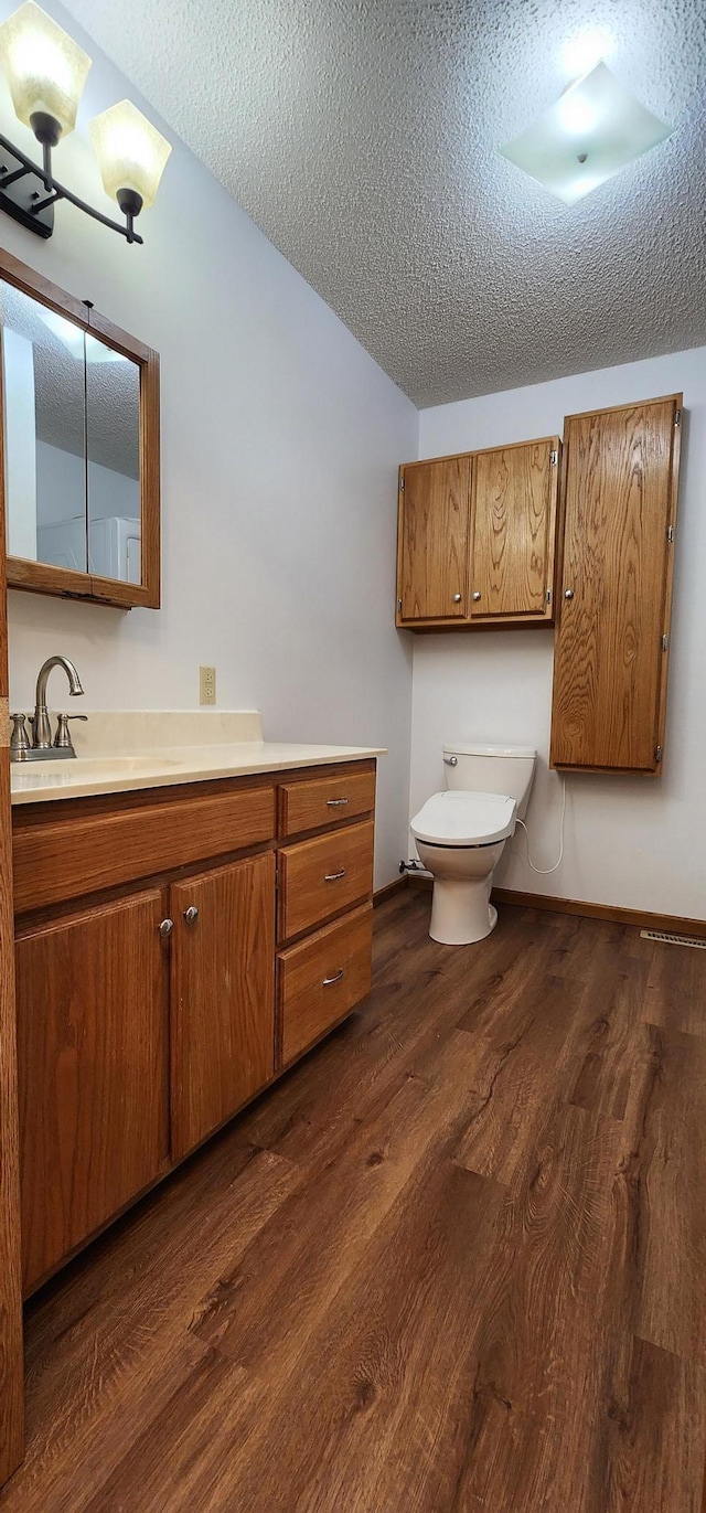 bathroom featuring a textured ceiling, toilet, vanity, and wood-type flooring