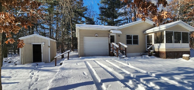 view of front of house with a storage shed, a sunroom, and a garage