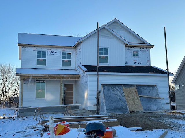 snow covered house featuring covered porch and a garage