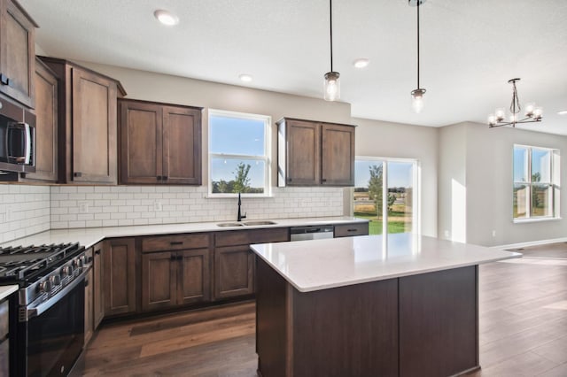 kitchen featuring appliances with stainless steel finishes, dark brown cabinetry, sink, decorative light fixtures, and a chandelier