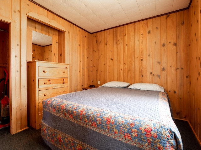 bedroom featuring wooden walls, crown molding, and dark carpet