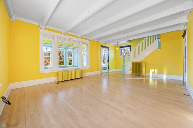 unfurnished living room with beam ceiling, radiator, hardwood / wood-style floors, and crown molding