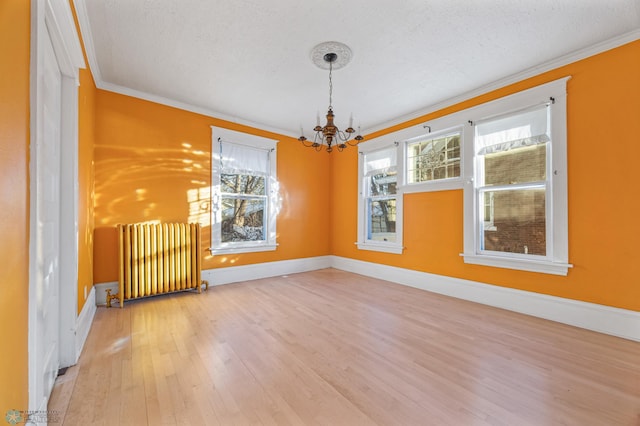 empty room with ornamental molding, radiator, plenty of natural light, and wood-type flooring