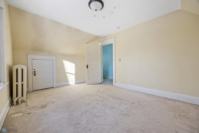 additional living space featuring carpet floors, radiator, and vaulted ceiling