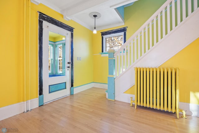 entrance foyer featuring stairs, ornamental molding, wood finished floors, and radiator