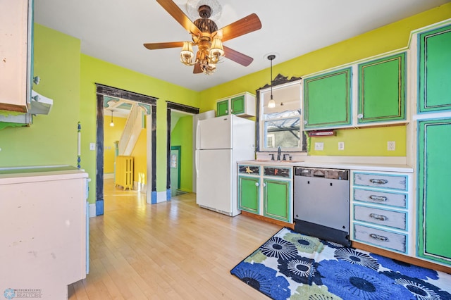 kitchen featuring decorative light fixtures, white appliances, light countertops, light wood finished floors, and washer / dryer