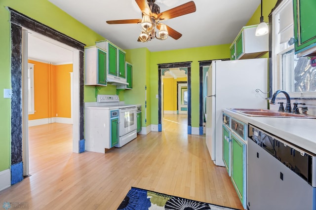 kitchen featuring white appliances, light wood finished floors, light countertops, pendant lighting, and a sink