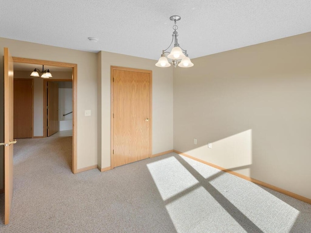 empty room with light carpet and an inviting chandelier